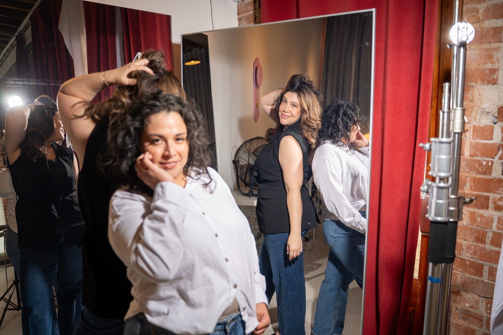 Mirror poses backstage between the red curtains